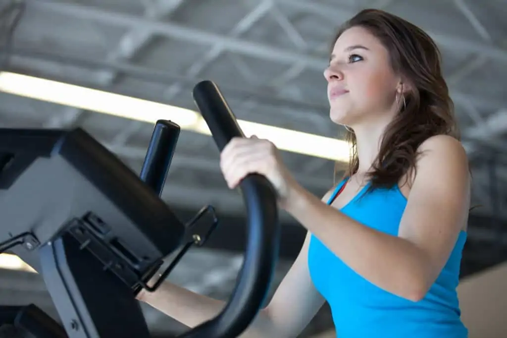 woman standing upright on a cardio machine - a decorative image in an article about stair climber workout mistakes