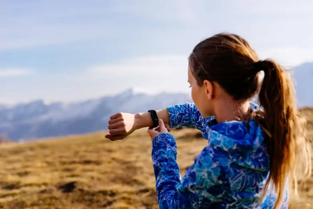 a woman outdoors looking at her fitness watch