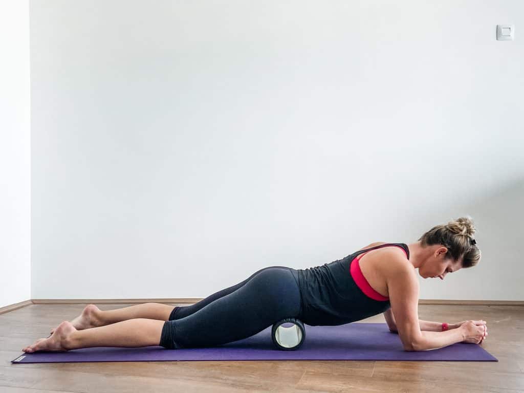 woman on a yoga mat using a foam roller in an article about how to fix tight hip flexors