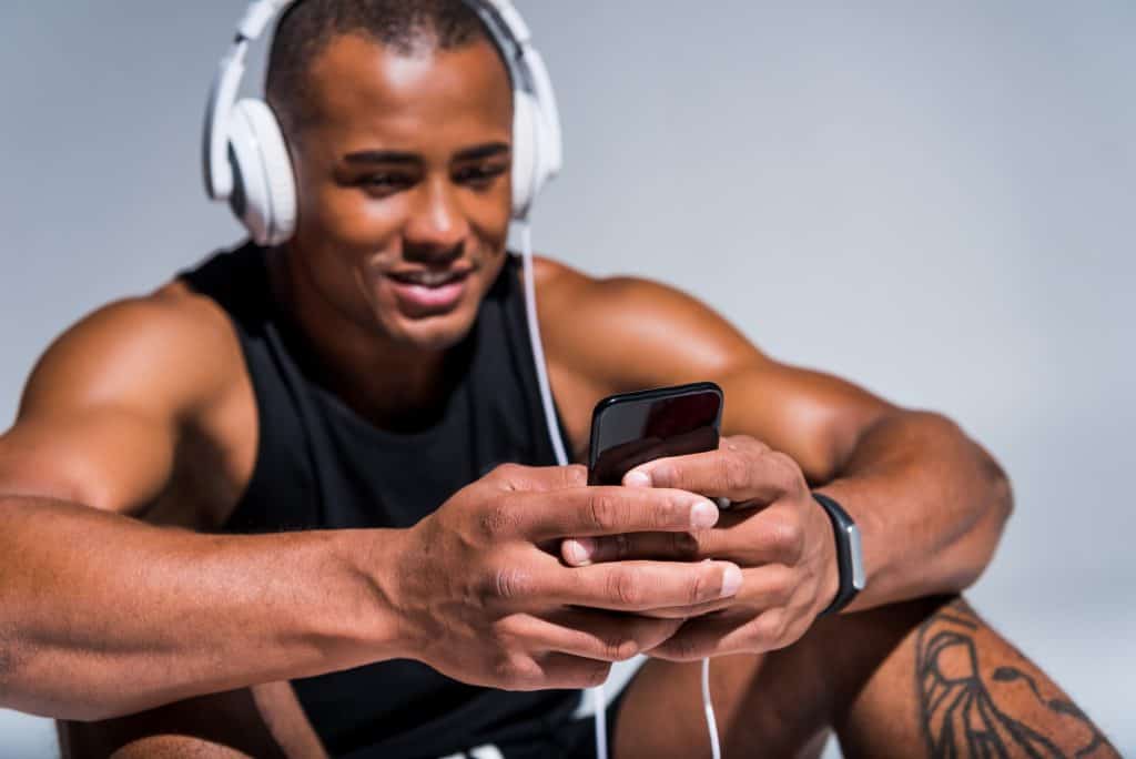man using his phone while working out. a decorative image in an aaptiv review article. 