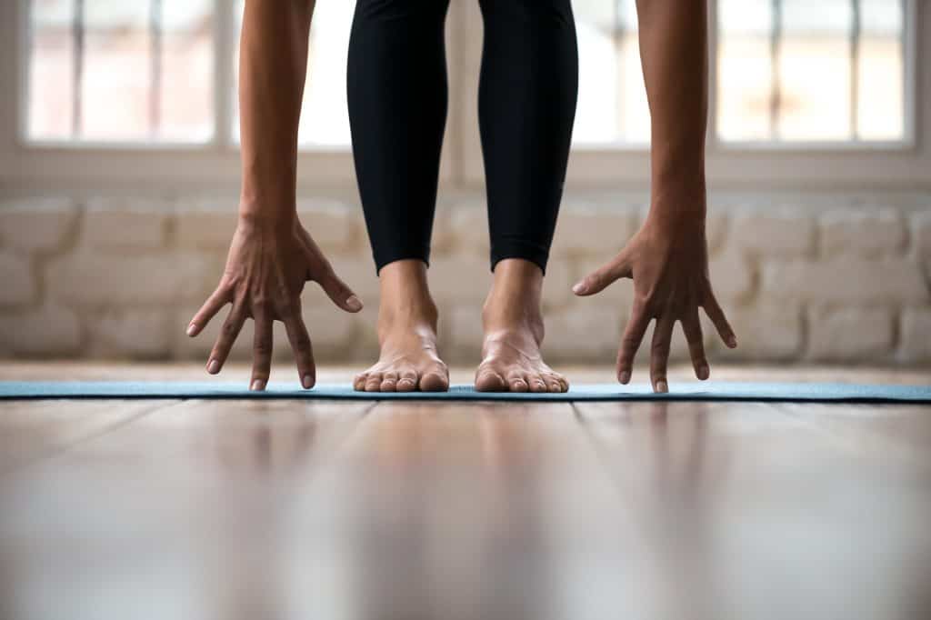 woman's feet and hands on a yoga mat decorative featured image for article about yoga mats for sweaty hands