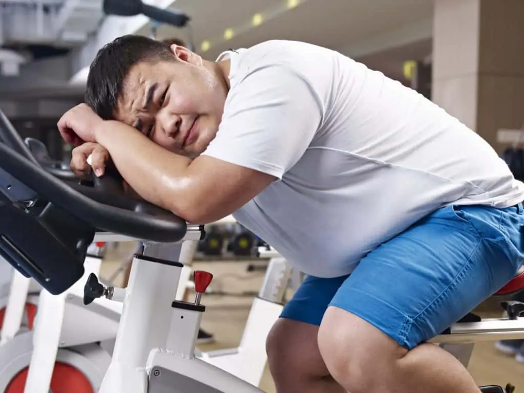 a man lying on a bike at the gym not enjoying exercise