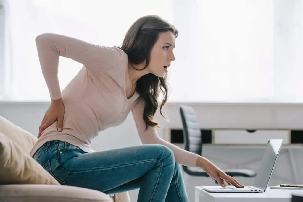 a woman using a computer with back pain