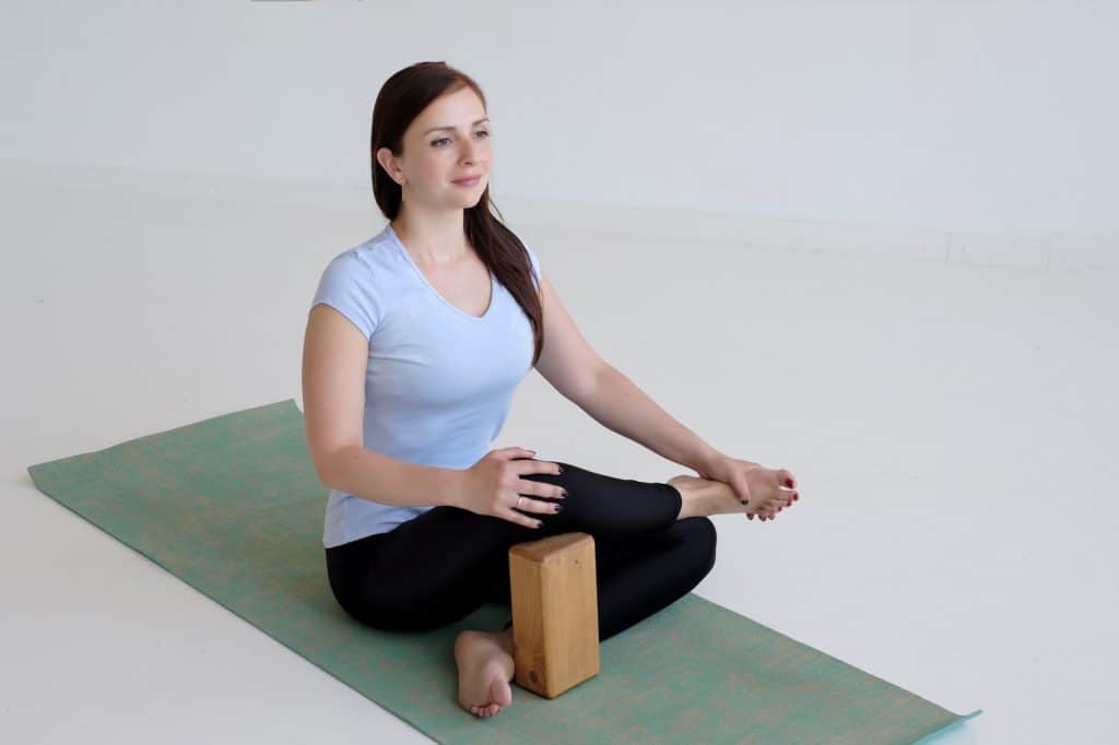 woman on a yoga mat using a block for knee support for yoga