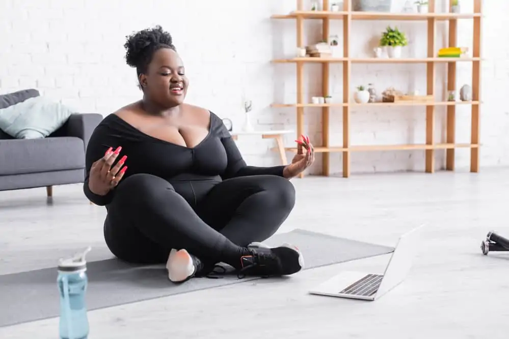 woman sitting on a yoga mat doing a virtual yoga class at home