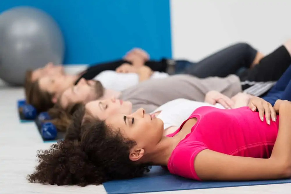 people lying down in a class performing deep breathing exercises