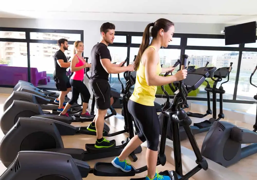 people at a gym using elliptical machines