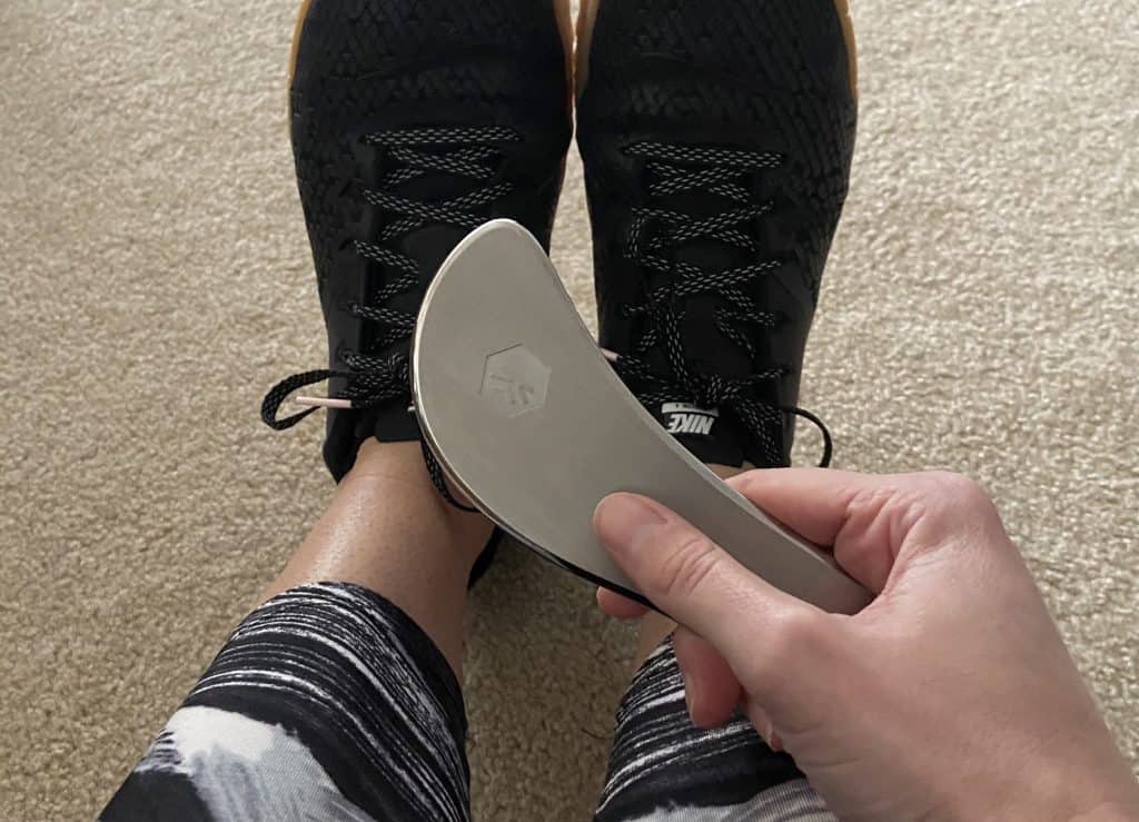 picture of a woman holding a fascia scraping tool - best plantar fasciitis scraping tool