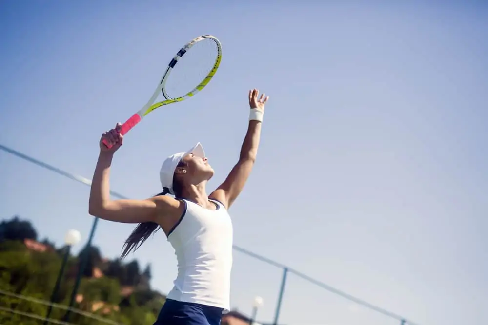 woman playing tennis serving a ball