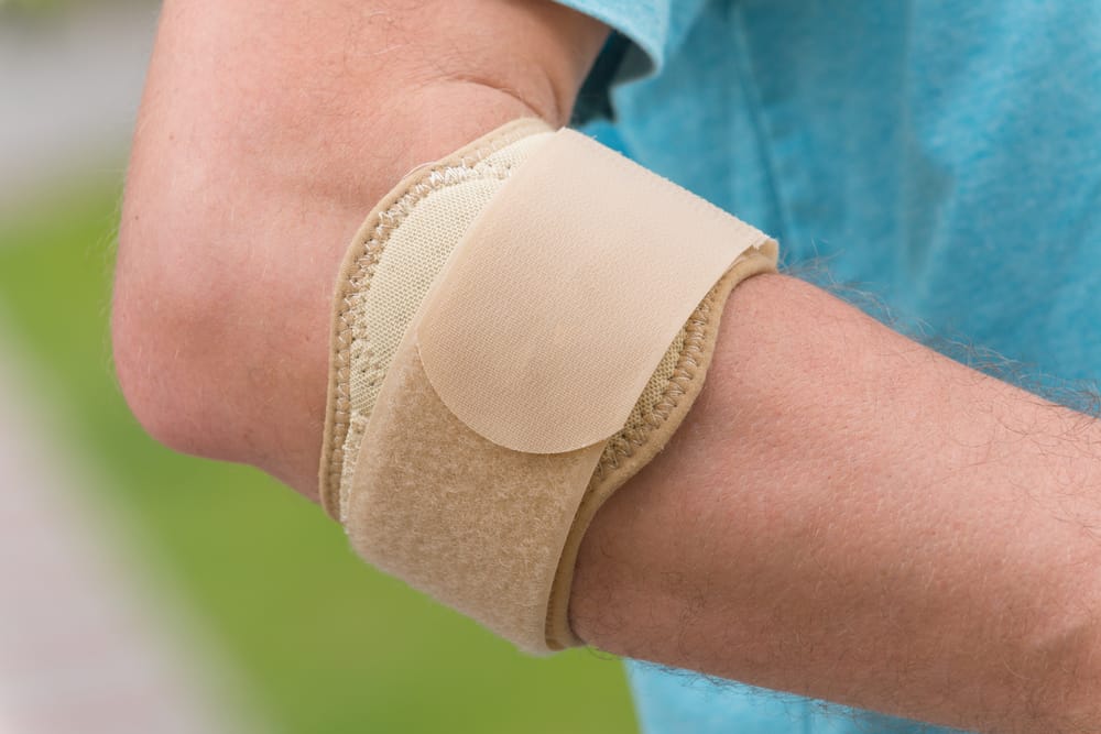 a man wearing a tennis elbow brace, visual for what makes tennis elbow worse