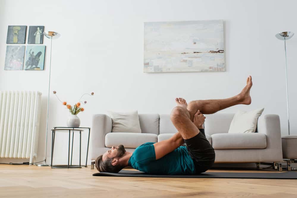 man doing yoga at home - decorative for article can yoga make sciatica worse?