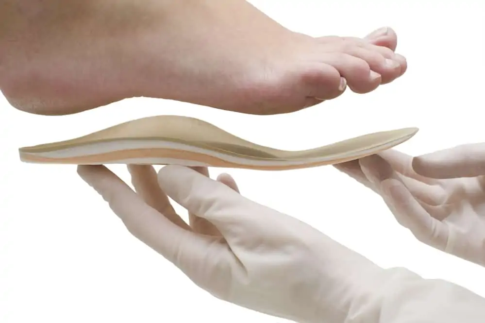 doctor holding an orthotic up to a foot