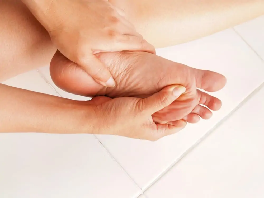 person rubbing painful foot - how to get rid of foot cramps