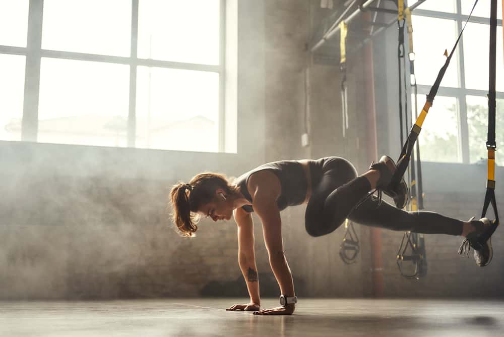 woman performing dynamic plank exercises with a TRX system