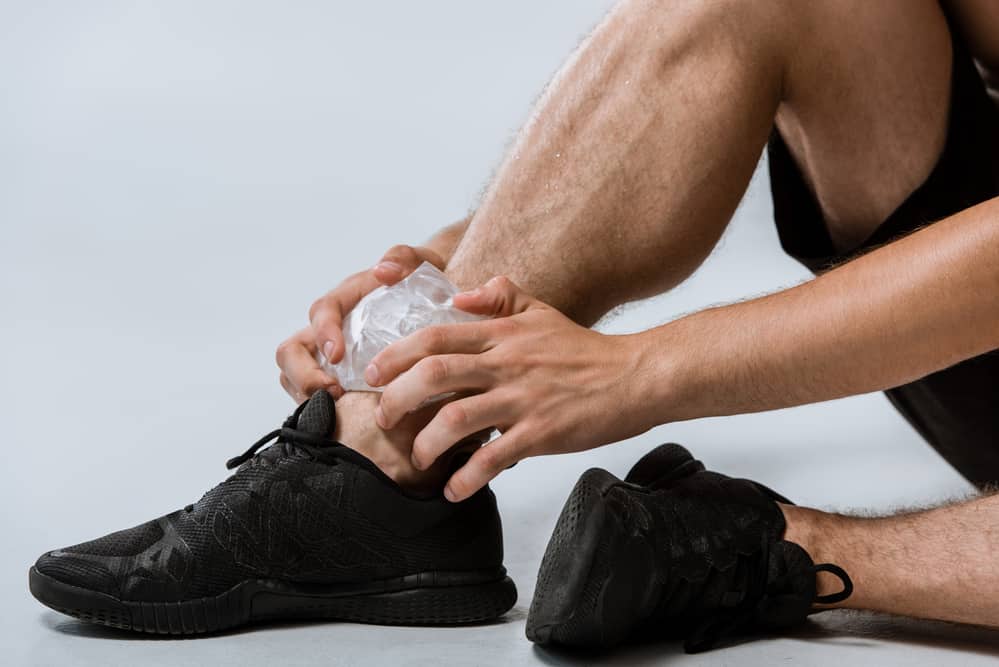 man holding ice on injured ankle