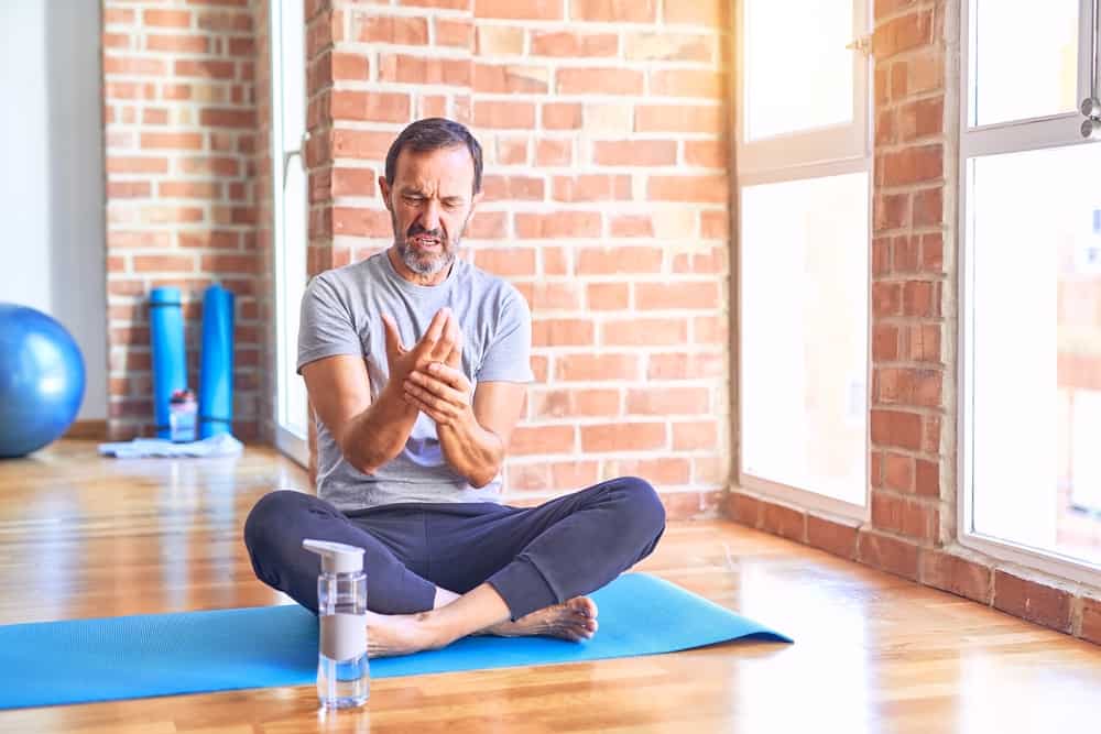 man doing yoga holding his wrist - wrist pain in yoga article
