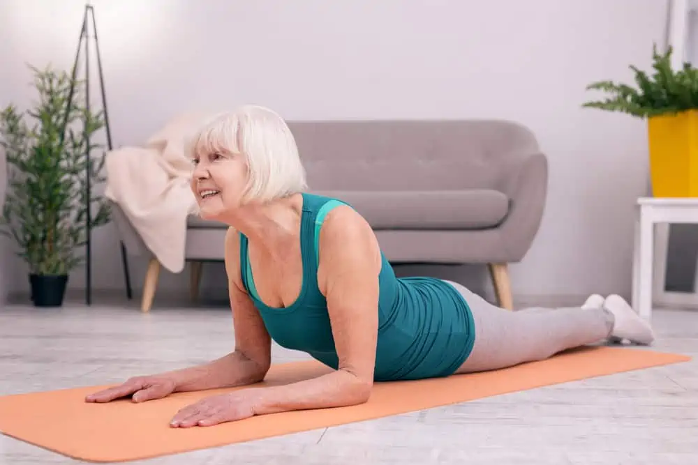 older woman doing sphinx pose - article about yoga poses to avoid with osteoporosis