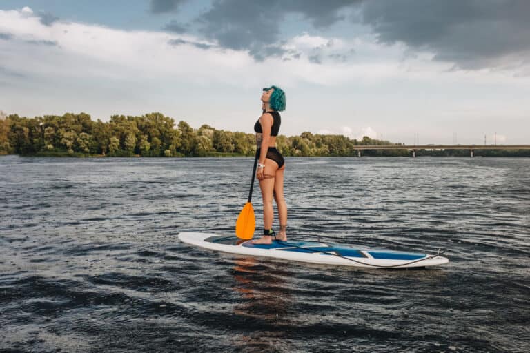 girl paddle boarding on a river - is paddle boarding good exercise?