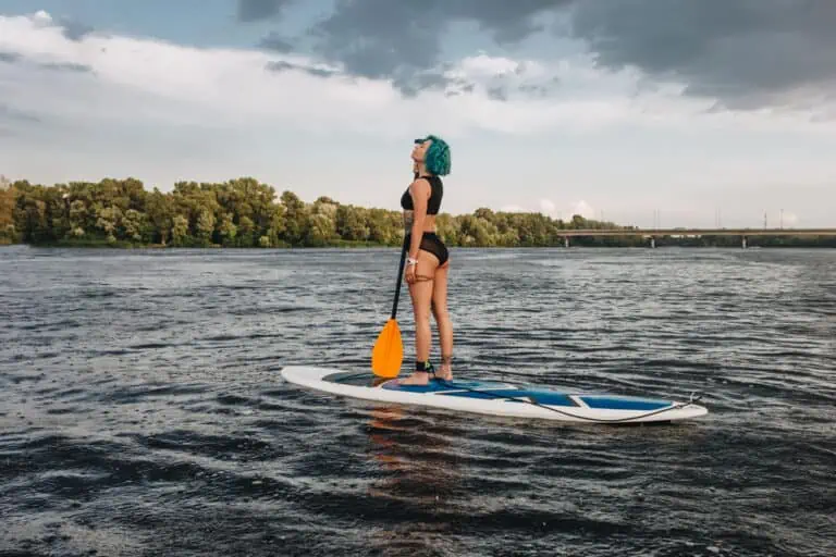 girl paddle boarding on a river - is paddle boarding good exercise?