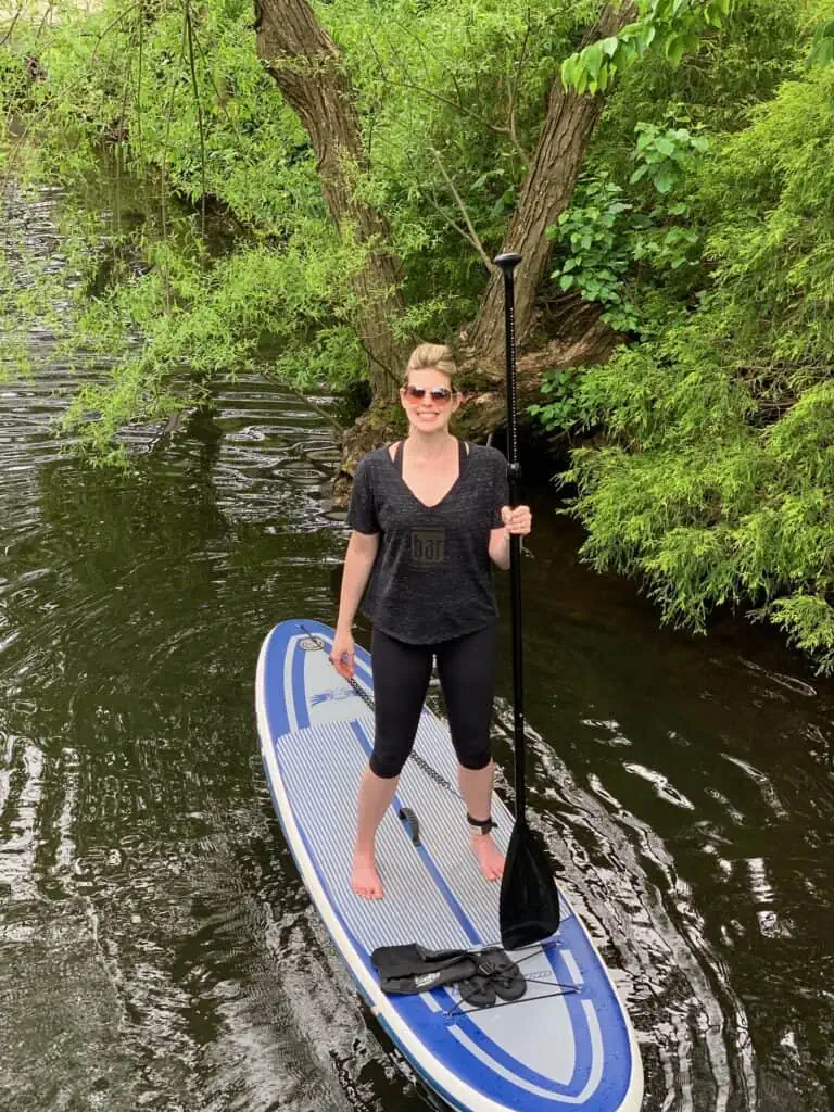 woman standing on a paddle board - is paddle boarding good exercise?
