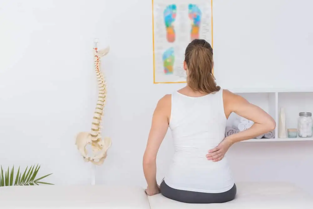 13 stretches for low back pain - woman in a physical therapy office with back pain
